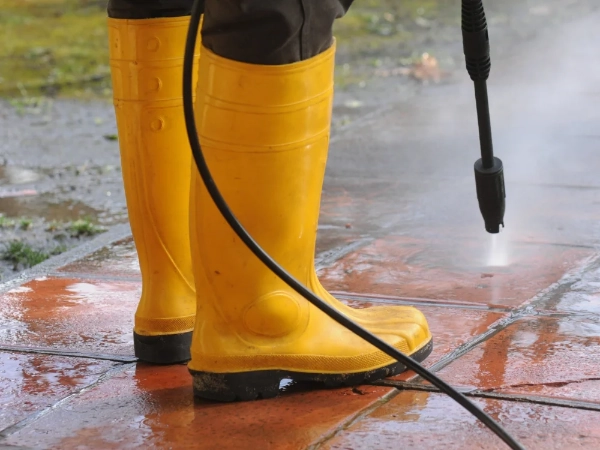 Mitarbeiter reinigt mit Hochdruckreiniger einen gepflasterten Außenbereich in Regensburg.